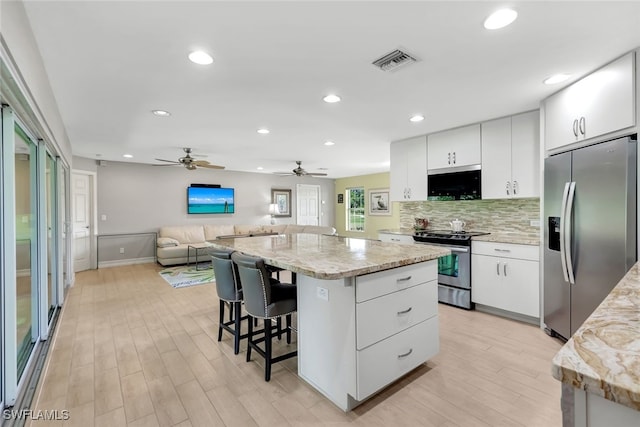 kitchen featuring white cabinets, stainless steel appliances, a kitchen island, and ceiling fan