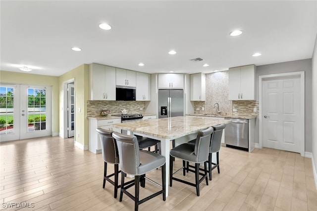 kitchen featuring light stone countertops, sink, a center island, a kitchen breakfast bar, and appliances with stainless steel finishes