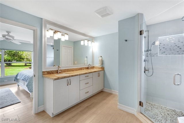 bathroom featuring hardwood / wood-style flooring, ceiling fan, a shower with door, and vanity