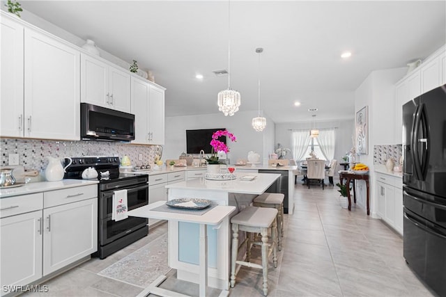 kitchen featuring a kitchen bar, black appliances, pendant lighting, white cabinets, and a kitchen island