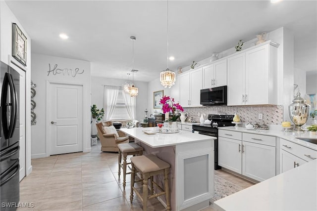 kitchen with white cabinets, decorative light fixtures, a center island, and electric range oven