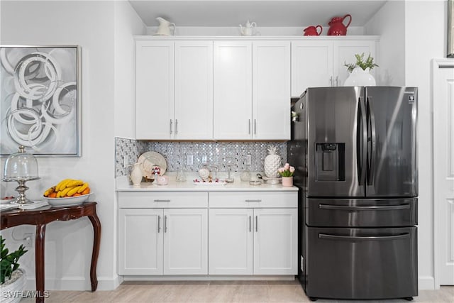 kitchen with white cabinets, decorative backsplash, light hardwood / wood-style floors, and stainless steel refrigerator with ice dispenser