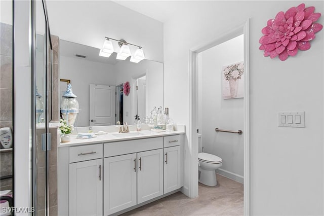 bathroom featuring tile patterned flooring, vanity, toilet, and walk in shower