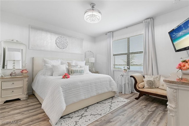 bedroom with light hardwood / wood-style flooring and an inviting chandelier