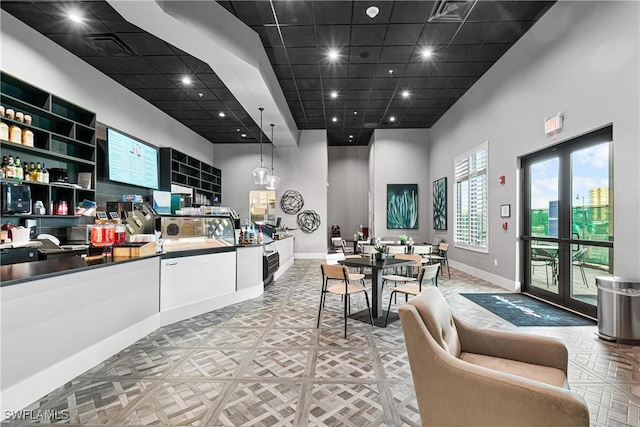 kitchen with pendant lighting, a paneled ceiling, white cabinets, and a towering ceiling