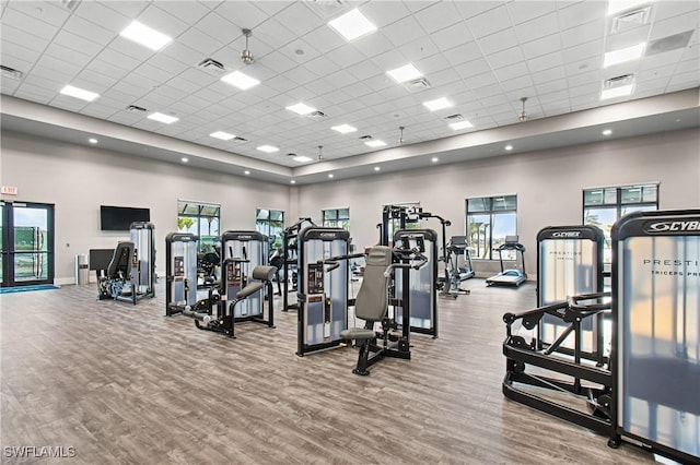 workout area with a drop ceiling, wood-type flooring, and a towering ceiling