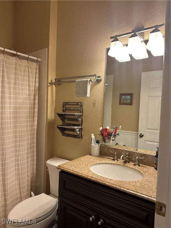 bathroom with vanity, curtained shower, and toilet