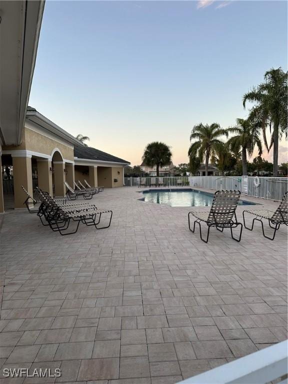 pool at dusk featuring a patio