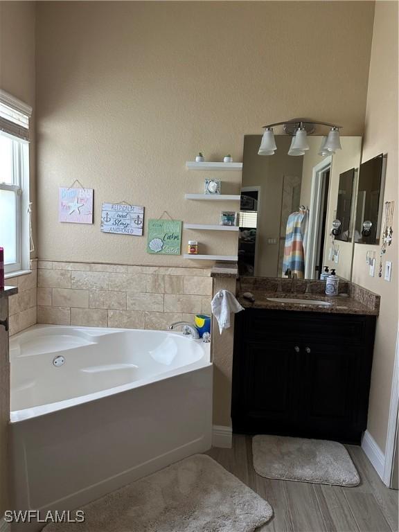 bathroom with vanity, hardwood / wood-style flooring, and a tub