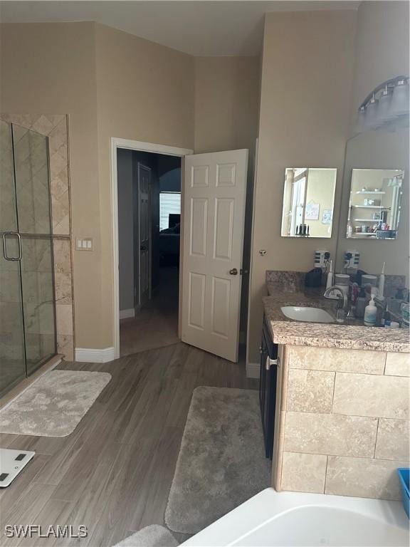 bathroom with wood-type flooring, vanity, and independent shower and bath