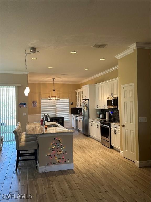 kitchen with white cabinets, sink, stainless steel appliances, and hanging light fixtures