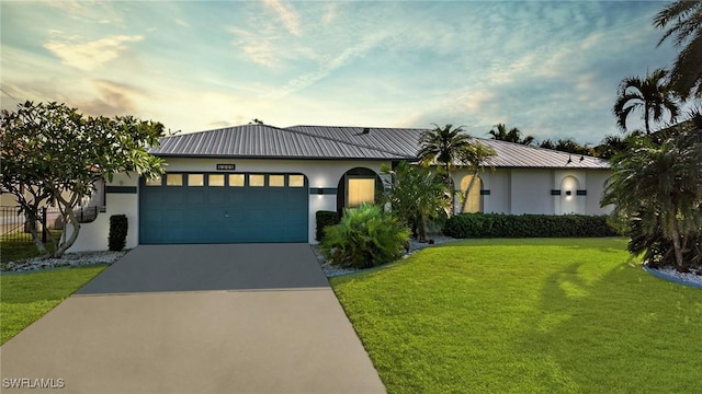 view of front facade featuring a garage, driveway, a front lawn, and stucco siding