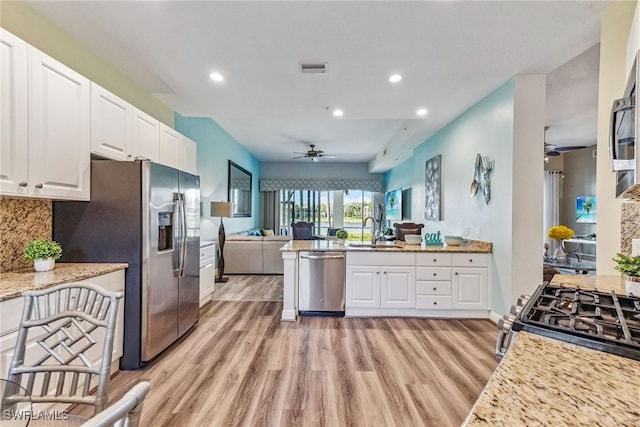 kitchen featuring stainless steel appliances, sink, white cabinets, decorative backsplash, and light stone countertops