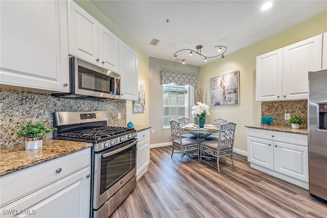 9275 Museo Cir Unit 103, Naples, FL 34114 - kitchen featuring light wood finished floors, white cabinetry, appliances with stainless steel finishes, baseboards, and decorative backsplash