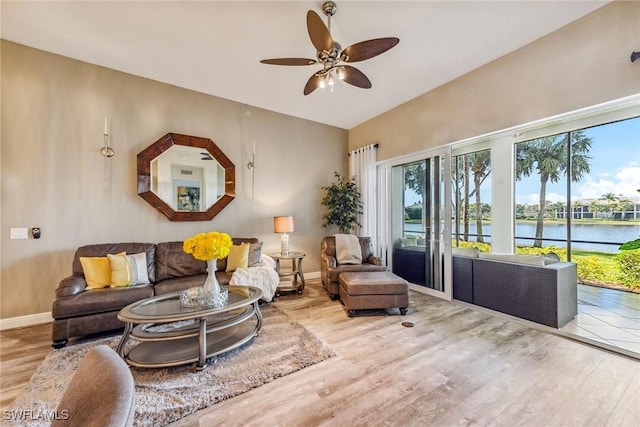 living room with ceiling fan, light wood-type flooring, and a water view