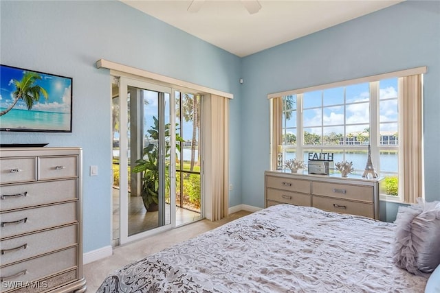 carpeted bedroom with multiple windows, ceiling fan, access to exterior, and a water view