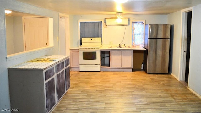 kitchen featuring tile counters, white range with electric stovetop, stainless steel fridge, and sink