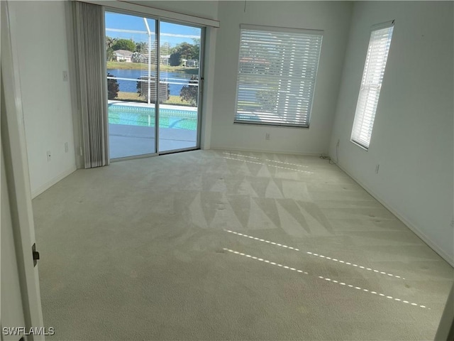 unfurnished room with light carpet and a water view