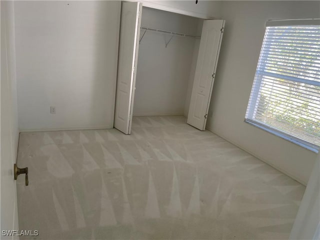 unfurnished bedroom with light colored carpet and a closet