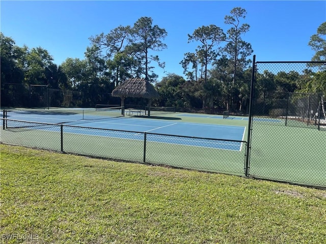 view of tennis court featuring a yard