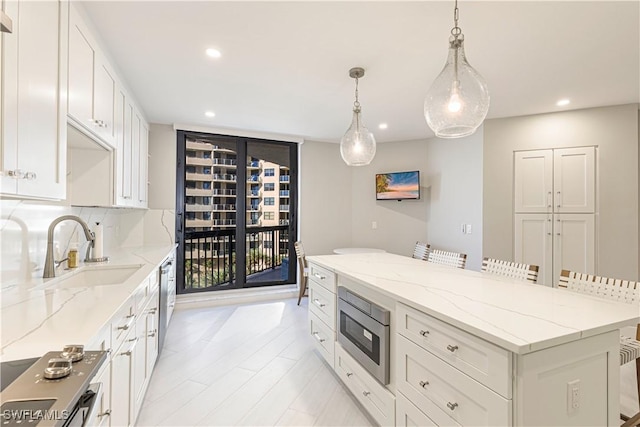 kitchen with sink, stainless steel appliances, decorative light fixtures, a breakfast bar area, and white cabinets