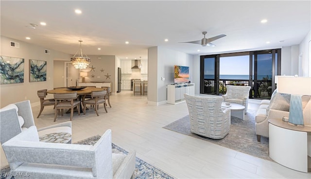 living area featuring baseboards, ceiling fan with notable chandelier, visible vents, and recessed lighting