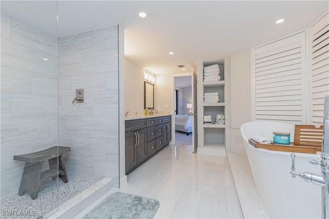 ensuite bathroom featuring ensuite bathroom, walk in shower, a freestanding bath, vanity, and recessed lighting