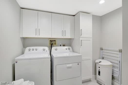 laundry area with cabinet space, radiator heating unit, and separate washer and dryer