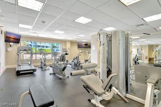 exercise room with a drop ceiling, visible vents, and baseboards