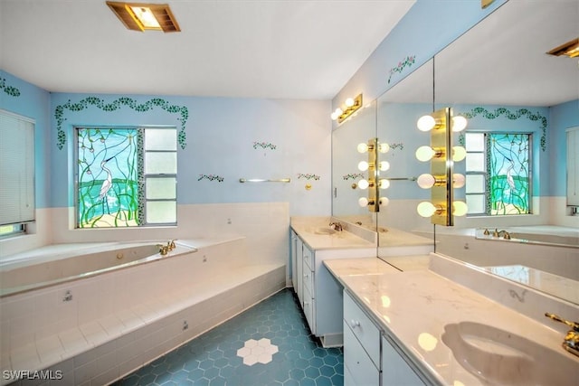 bathroom featuring vanity, a relaxing tiled tub, a wealth of natural light, and tile patterned floors