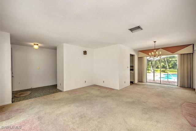 unfurnished room featuring light colored carpet and a chandelier