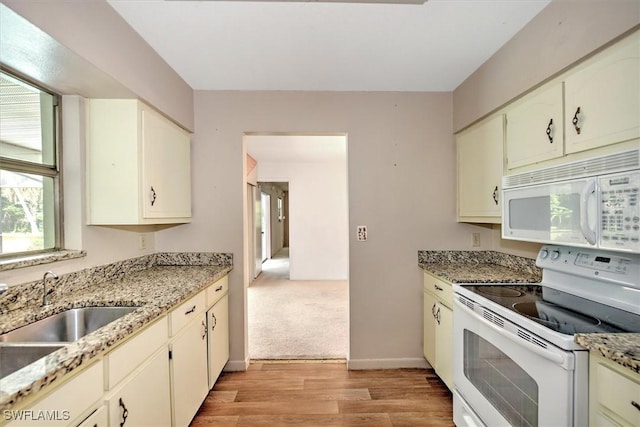 kitchen featuring light stone countertops, sink, white appliances, and light wood-type flooring