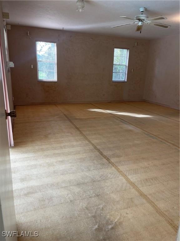 unfurnished room with ceiling fan and a healthy amount of sunlight