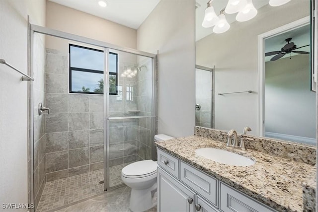 bathroom featuring a shower with door, vanity, ceiling fan, and toilet