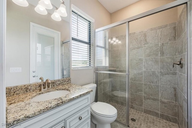 bathroom featuring vanity, toilet, a shower with shower door, and a notable chandelier