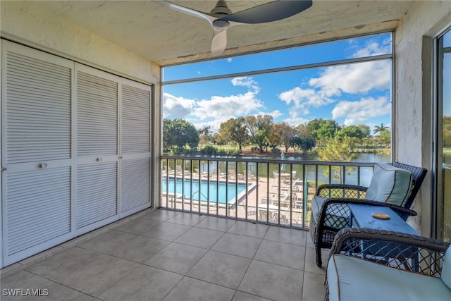 sunroom / solarium featuring ceiling fan and a water view