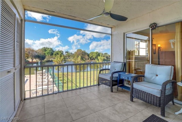 sunroom featuring ceiling fan and a water view