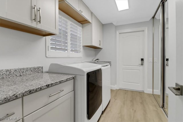 washroom with cabinets, light hardwood / wood-style flooring, and washer and clothes dryer