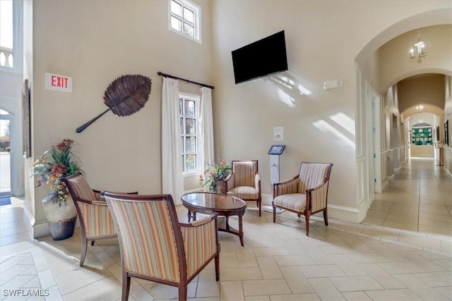 living area with light tile patterned floors, a towering ceiling, and a notable chandelier