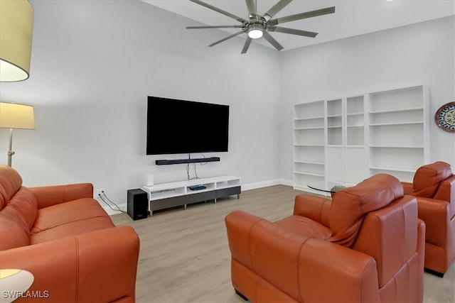 living room with baseboards, a ceiling fan, and light wood-style flooring