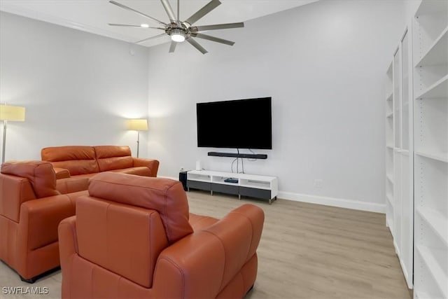 living area featuring baseboards, a ceiling fan, and light wood-style flooring