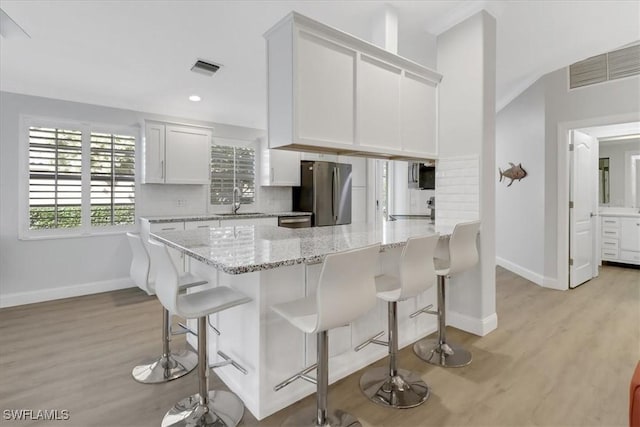 kitchen featuring a sink, appliances with stainless steel finishes, a kitchen bar, and light wood-type flooring