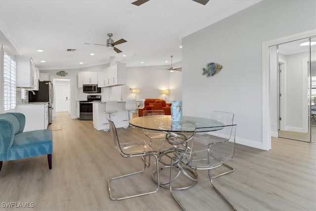dining space featuring light wood-style floors, ornamental molding, and a ceiling fan