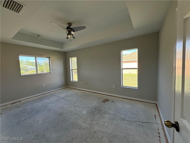 empty room with ceiling fan and a raised ceiling