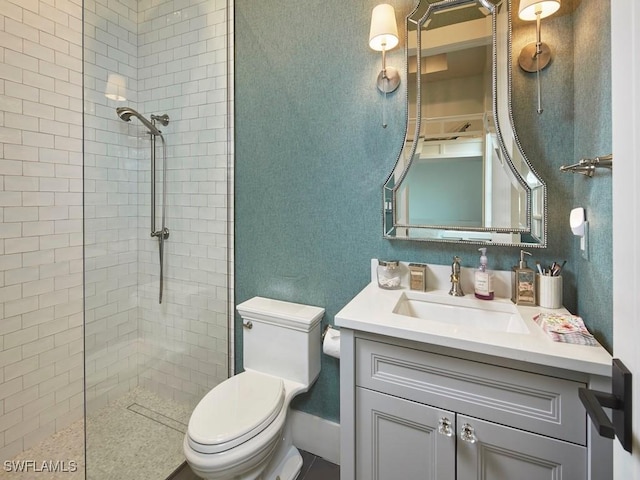 bathroom featuring tiled shower, toilet, and vanity