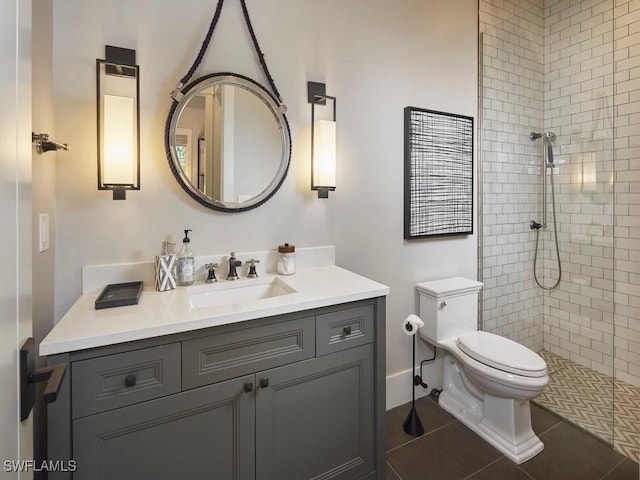 bathroom with tile patterned floors, vanity, a tile shower, and toilet