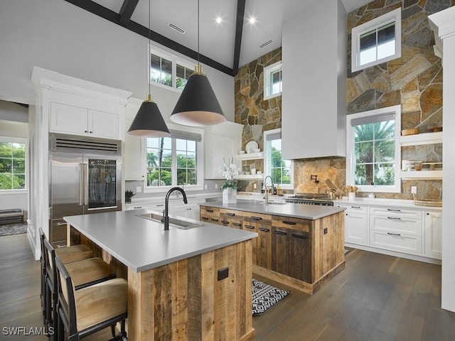 kitchen featuring sink, white cabinetry, a center island with sink, and stainless steel built in fridge