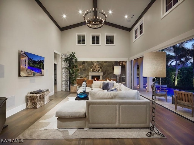 living room with hardwood / wood-style floors, a fireplace, a notable chandelier, high vaulted ceiling, and crown molding