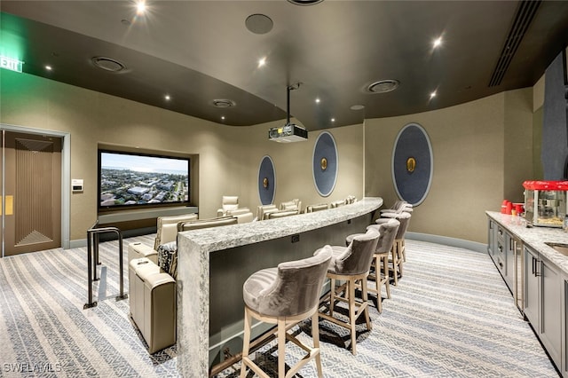 carpeted home theater featuring bar area