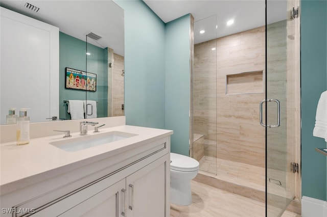 bathroom featuring vanity, toilet, and a shower with shower door